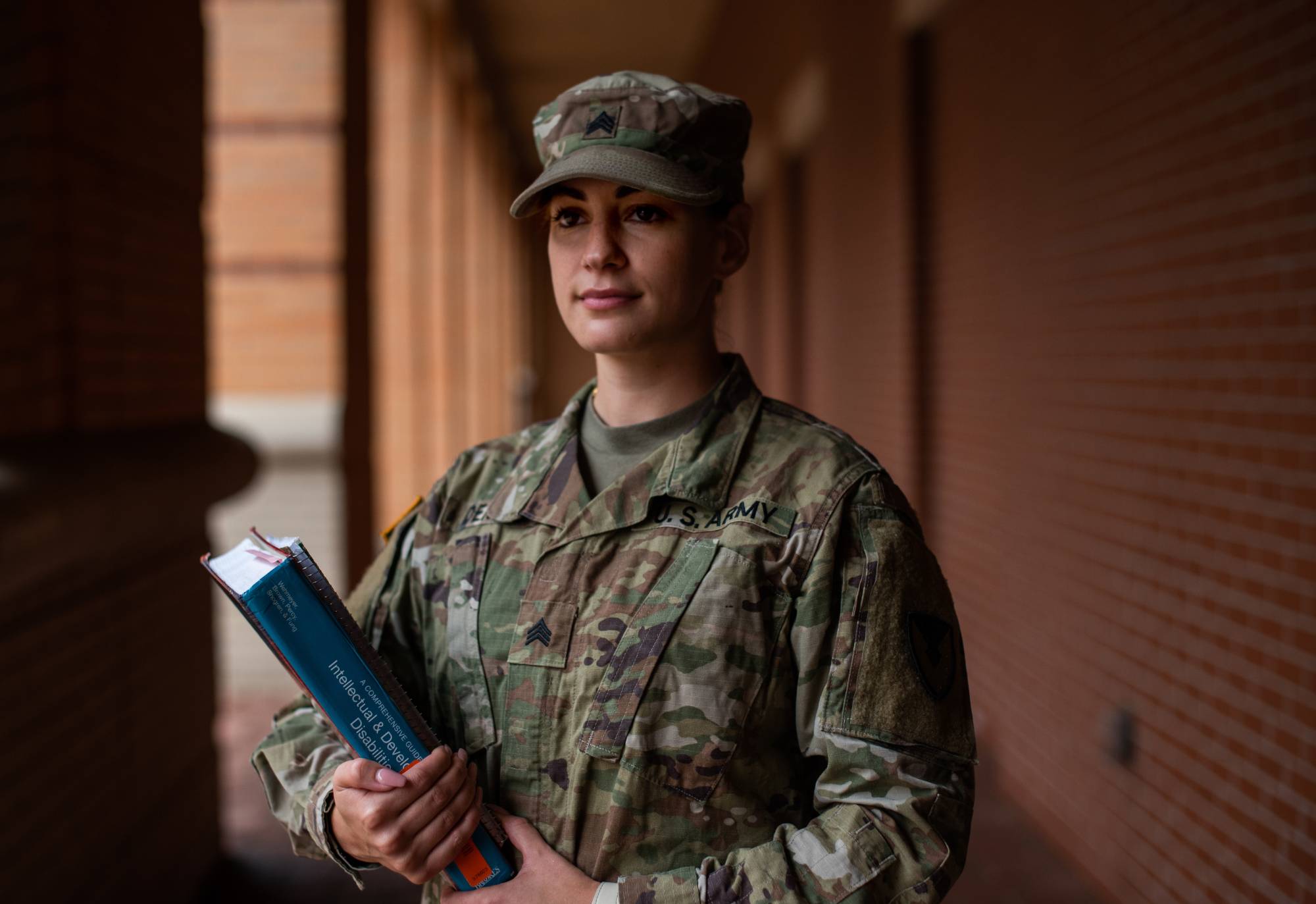 woman wearing army uniform holding books on campus